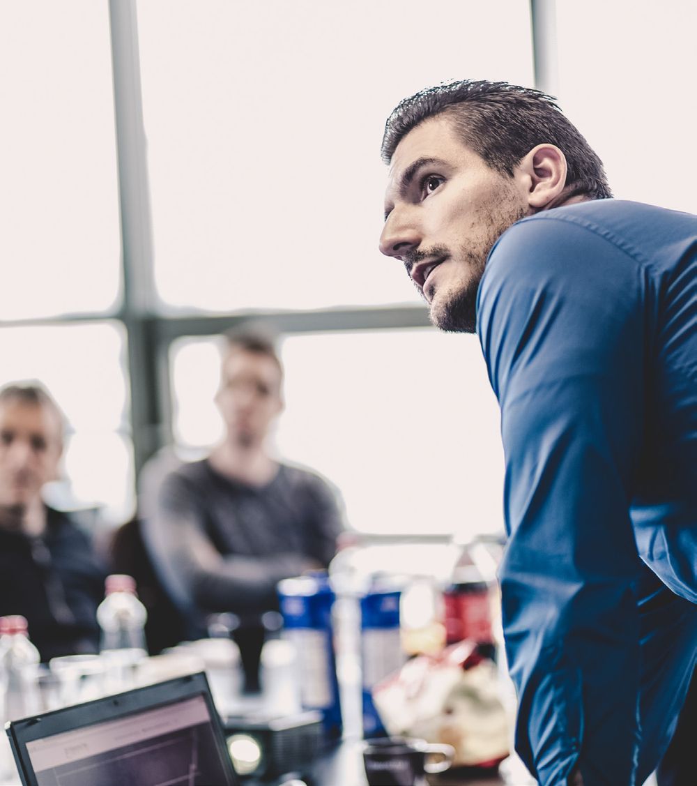 A Nexova expert looking up at a presentation, with colleagues behind him